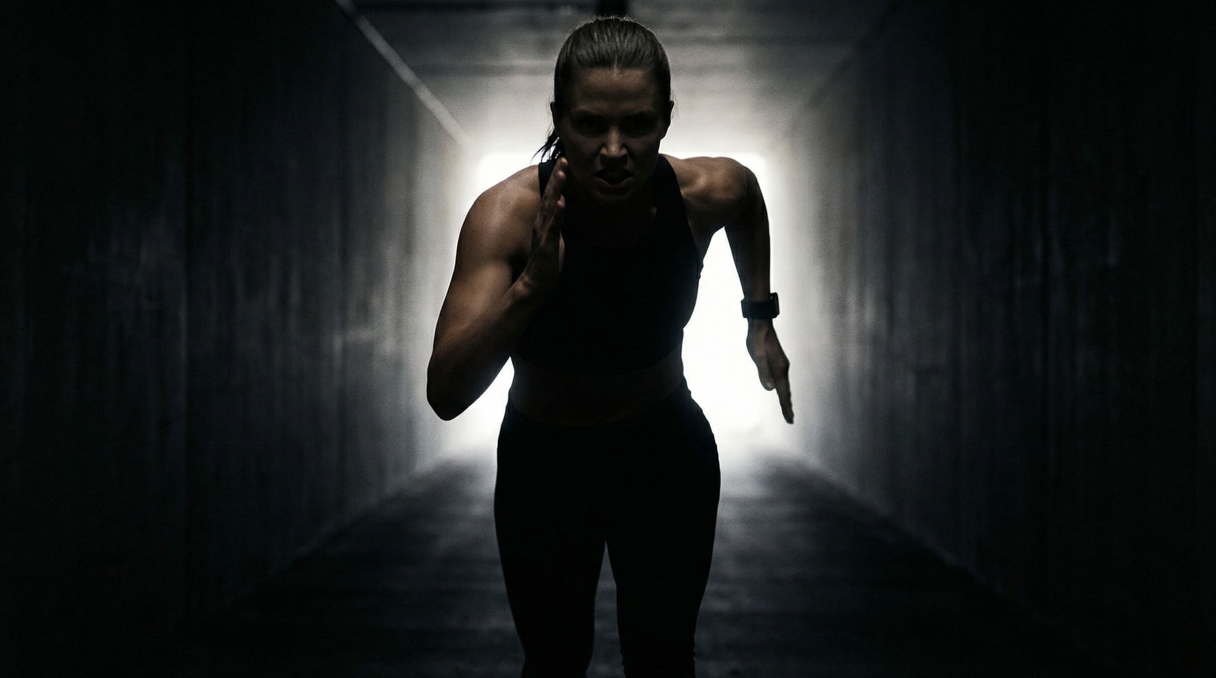 Person running in a dark tunnel with a bright light at the end